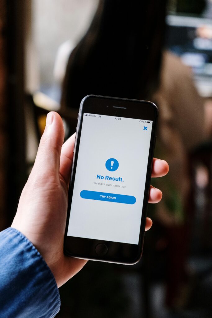 Pessoa segurando smartphone exibindo mensagem de erro "No Result", ilustrando a ocorrência de bug em aplicativos e sistemas digitais.