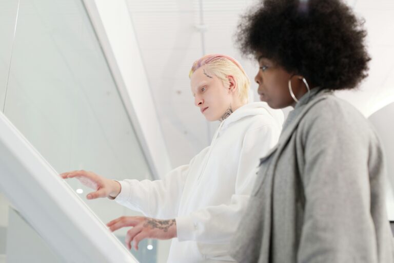 Dois profissionais de tecnologia colaboram usando uma tela touch, representando o conceito de desenvolvimento full stack com integração entre front-end e back-end.