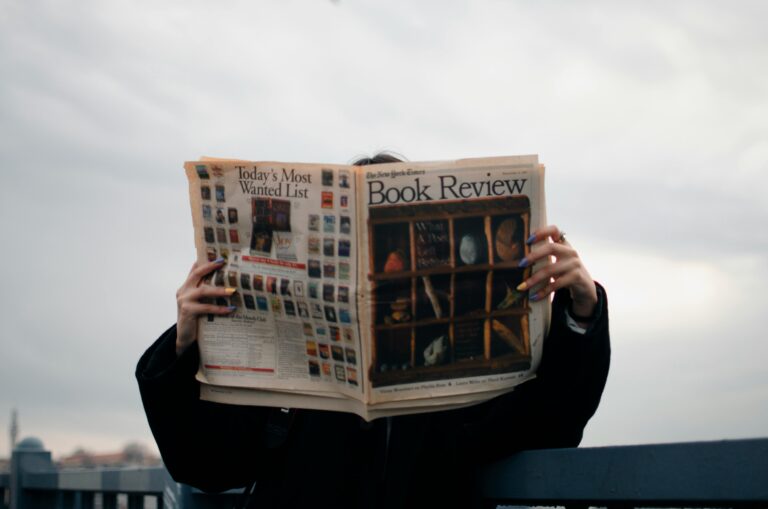 Pessoa lendo jornal com manchetes visíveis, simbolizando a comunicação de atualizações e novidades em produtos digitais, como nas práticas de update.