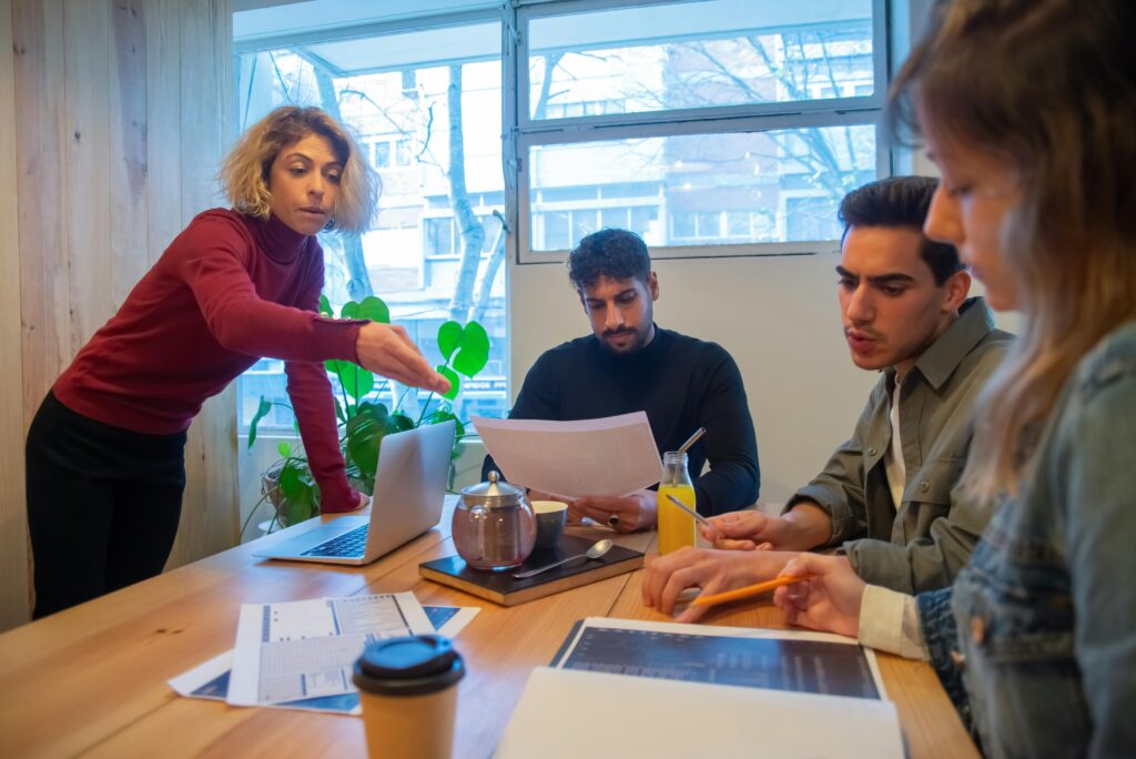 Equipe reunida em uma sala de reunião analisando documentos e gráficos, representando o planejamento de releases e melhorias na experiência do usuário em produtos digitais.