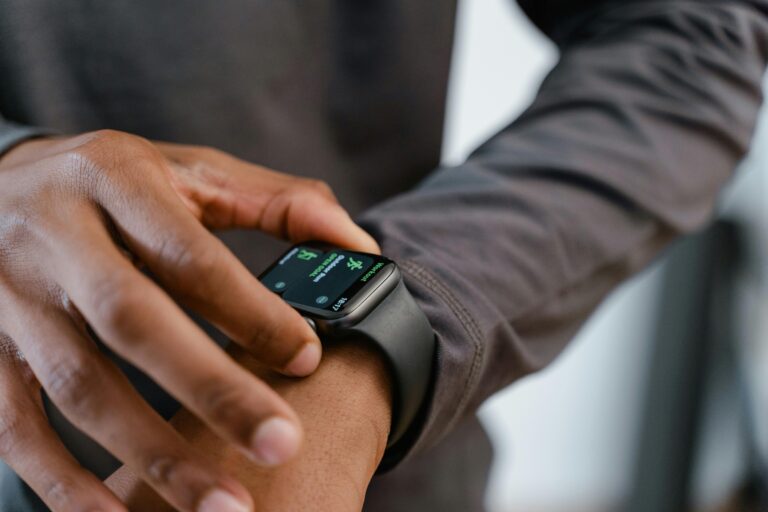 Pessoa interagindo com smartwatch preto, representando tecnologia vestível conectada à Internet das Coisas.