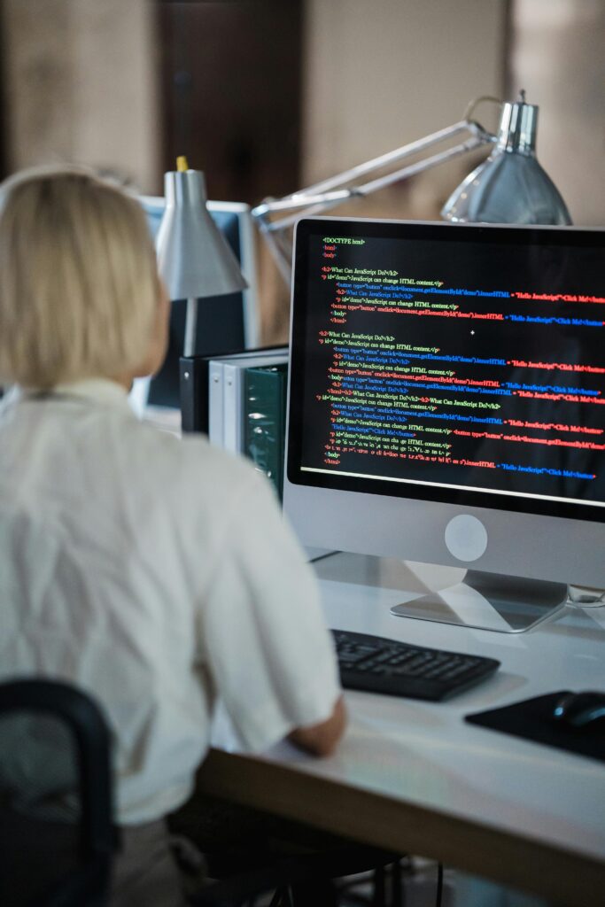 Pessoa desenvolvendo front-end em tela de computador com códigos HTML e CSS.