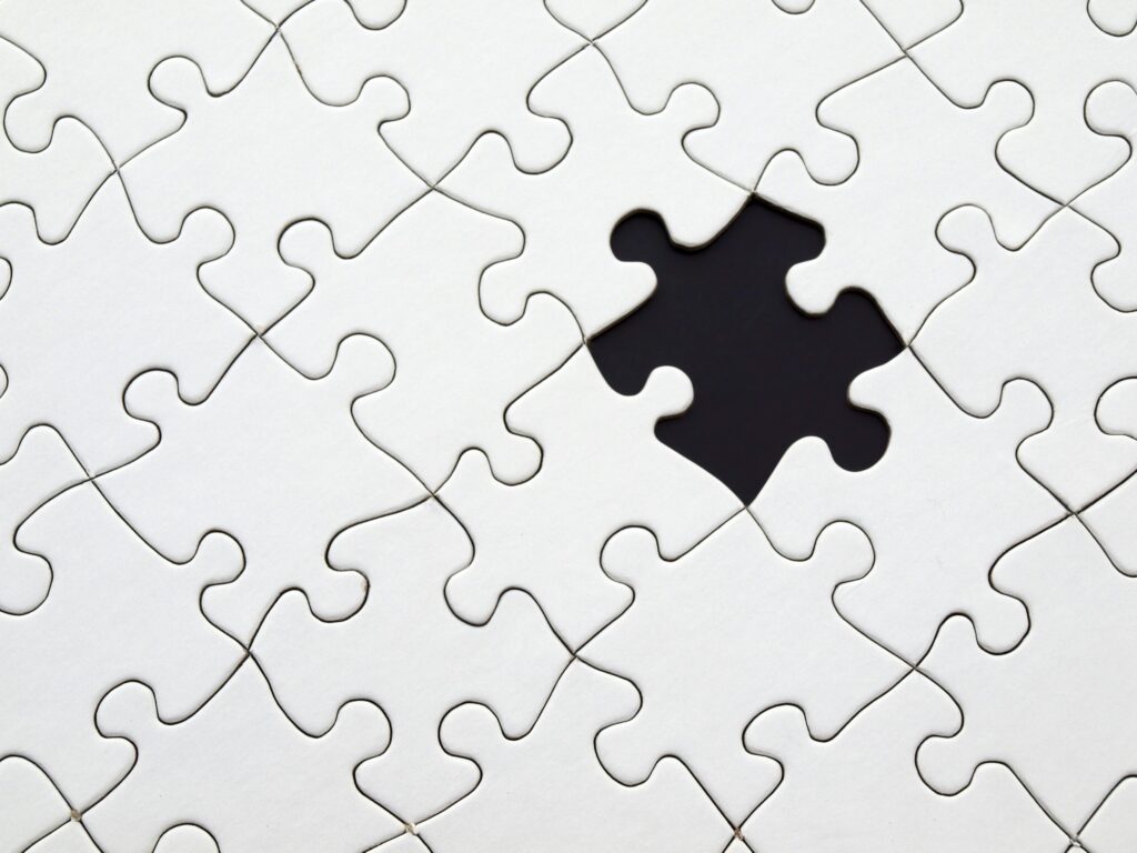 Quebra-cabeça branco com uma peça faltando no centro, simbolizando a importância dos KPIs como elementos cruciais para completar a visão estratégica de um negócio.