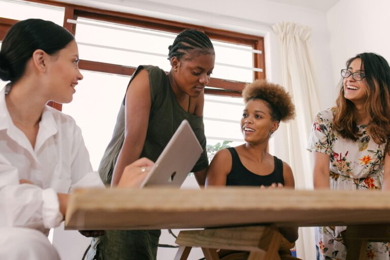 Mulheres diversas em reunião colaborativa com notebook, discutindo soluções tecnológicas baseadas em Edge Computing.