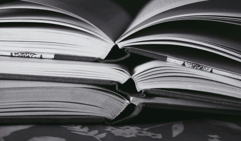 Livros empilhados e abertos representando a organização, o armazenamento seguro de informações e a colaboração contínua em repositórios de código e projetos digitais.
