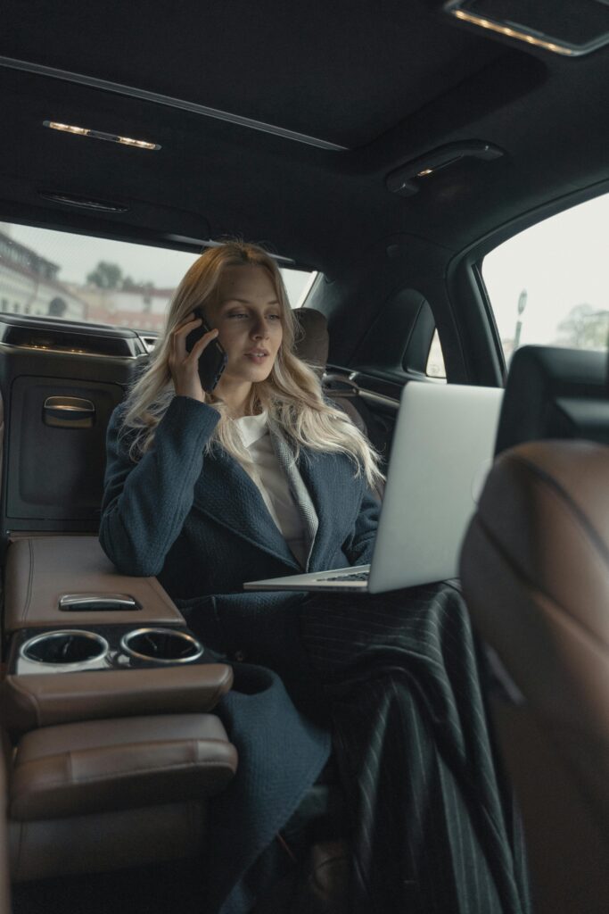 Pessoa concentrada com notebook no colo enquanto fala ao telefone dentro de um carro, simbolizando produtividade em movimento e gerenciamento de tempo com o método Pomodoro.