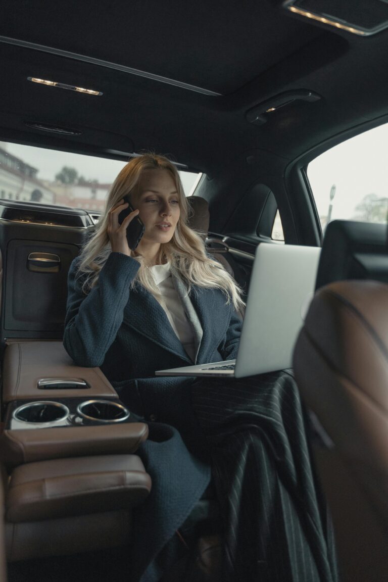 Pessoa concentrada com notebook no colo enquanto fala ao telefone dentro de um carro, simbolizando produtividade em movimento e gerenciamento de tempo com o método Pomodoro.