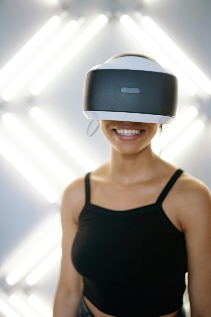 Mulher sorridente usando headset de realidade aumentada, em ambiente iluminado com luzes futuristas ao fundo.