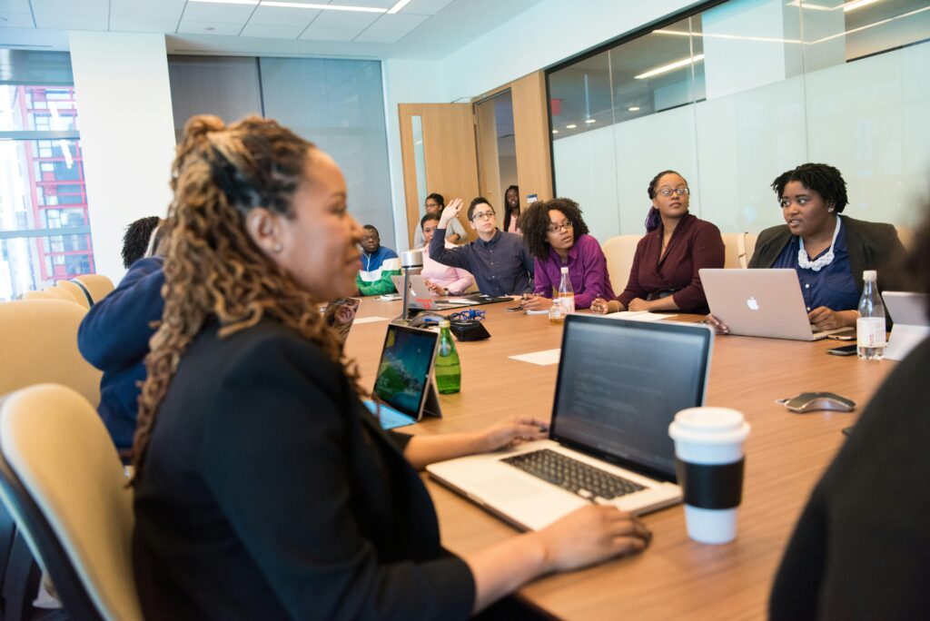 Profissionais reunidos em sala de reunião com notebooks abertos, analisando dados e discutindo como adaptar os sistemas corporativos à possível inclusão de letras no CNPJ.