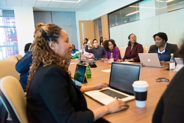 Profissionais reunidos em sala de reunião com notebooks abertos, analisando dados e discutindo como adaptar os sistemas corporativos à possível inclusão de letras no CNPJ.