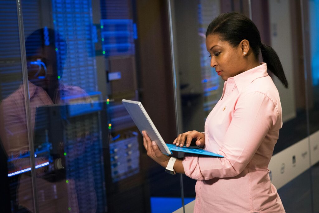 Profissional operando um notebook diante de servidores em data center, representando o trabalho com Big Data e infraestrutura de análise de dados em larga escala.
