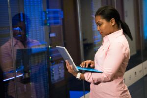 Profissional operando um notebook diante de servidores em data center, representando o trabalho com Big Data e infraestrutura de análise de dados em larga escala.