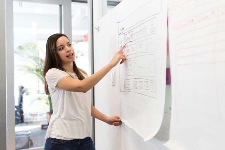 Mulher apresentando protótipo de interface em papel, durante atividade de UX Research focada na experiência do usuário e testes de usabilidade.