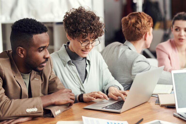 Profissionais colaborando em equipe com notebooks e gráficos sobre a mesa, representando o uso de hardware no ambiente corporativo.