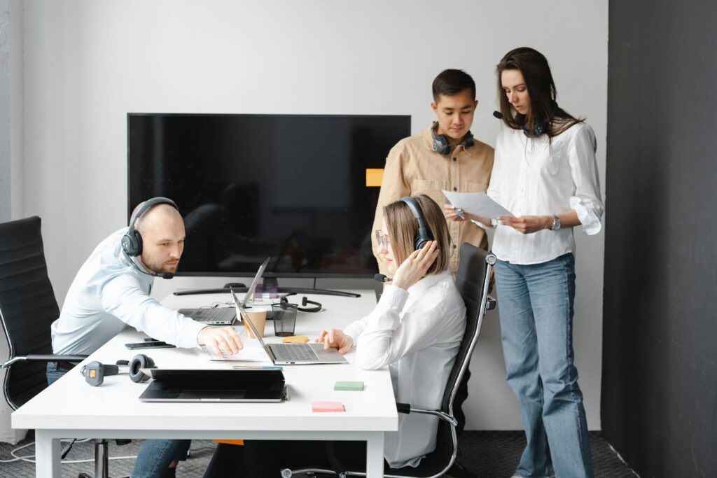 Quatro profissionais de tecnologia reunidos em um ambiente corporativo, usando headsets e laptops, colaborando sobre soluções de segurança digital com foco em SSL (Secure Sockets Layer).