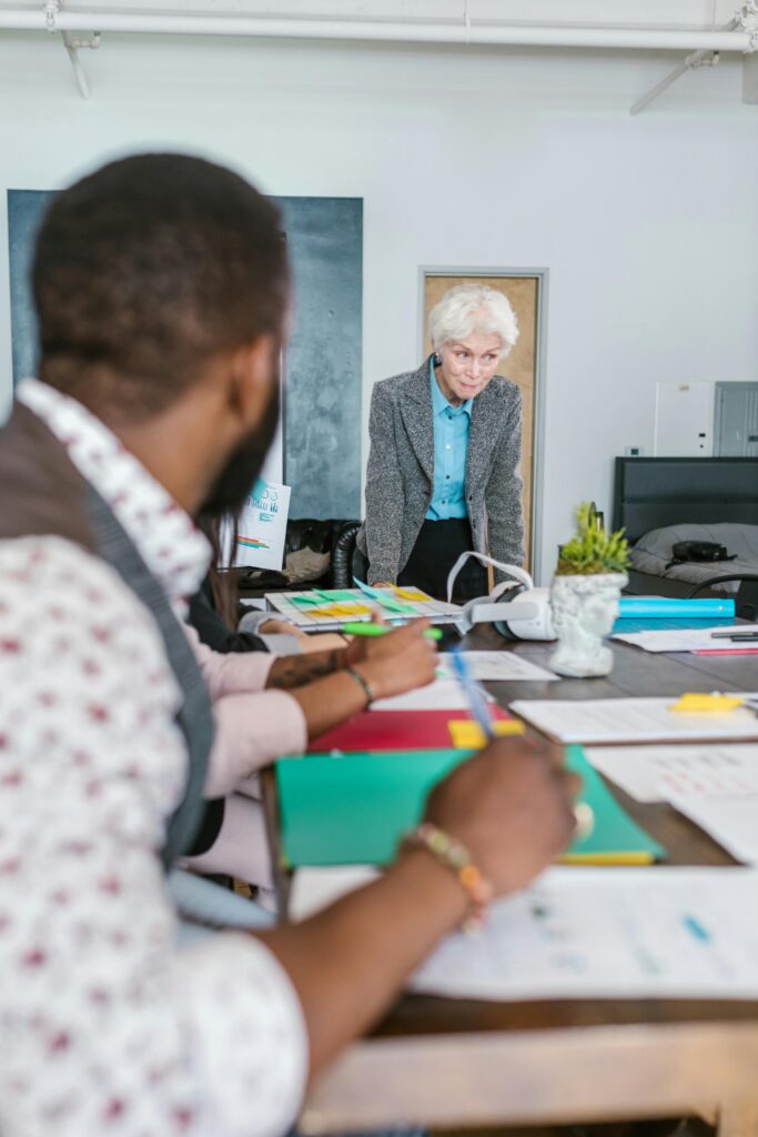 Pessoas reunidas em uma mesa de reunião analisando documentos, representando colaboração e planejamento estratégico em um projeto de crowdfunding.
