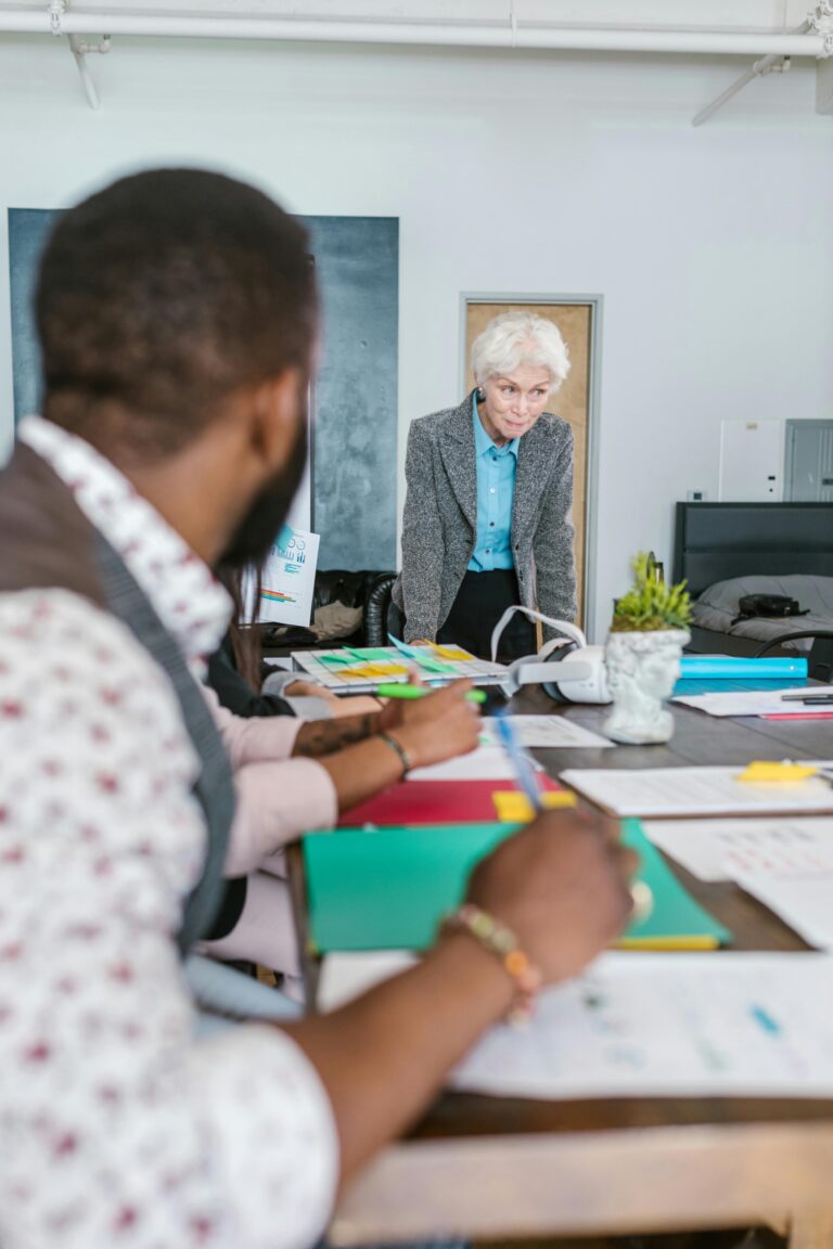 Pessoas reunidas em uma mesa de reunião analisando documentos, representando colaboração e planejamento estratégico em um projeto de crowdfunding.