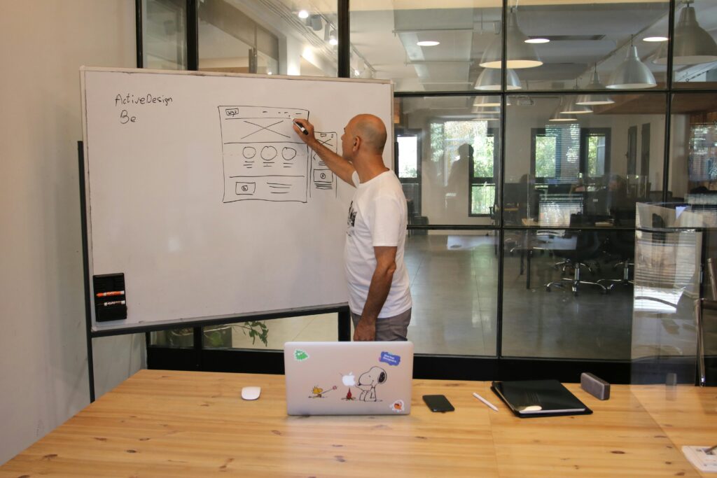 Profissional esboçando wireframe de interface em lousa, enquanto planeja conteúdo e fluxos de UX Writing para um produto digital.