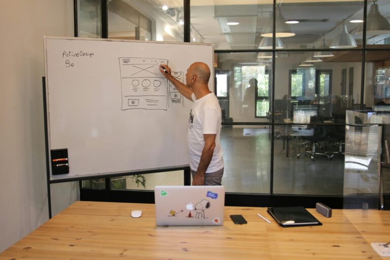 Profissional esboçando wireframe de interface em lousa, enquanto planeja conteúdo e fluxos de UX Writing para um produto digital.