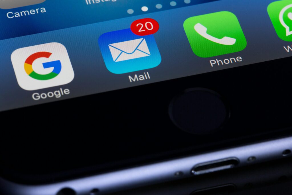 Ícone do aplicativo de e-mail em um smartphone com 20 mensagens não lidas, sugerindo acúmulo na caixa de entrada.
