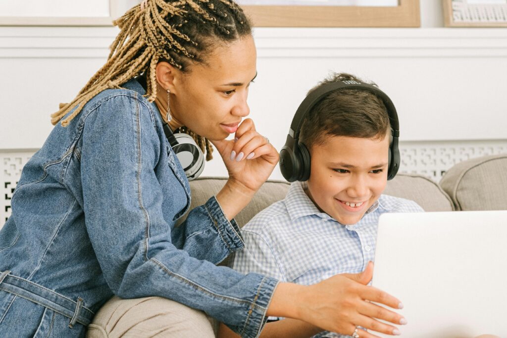 Mulher ajudando um menino em atividade online, representando desafios do ensino digital e impacto da fragmentação de sistemas educacionais.