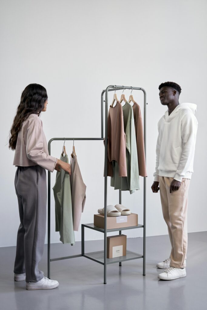 Dois consumidores observando roupas em exposição minimalista, com foco em experiência de compra.