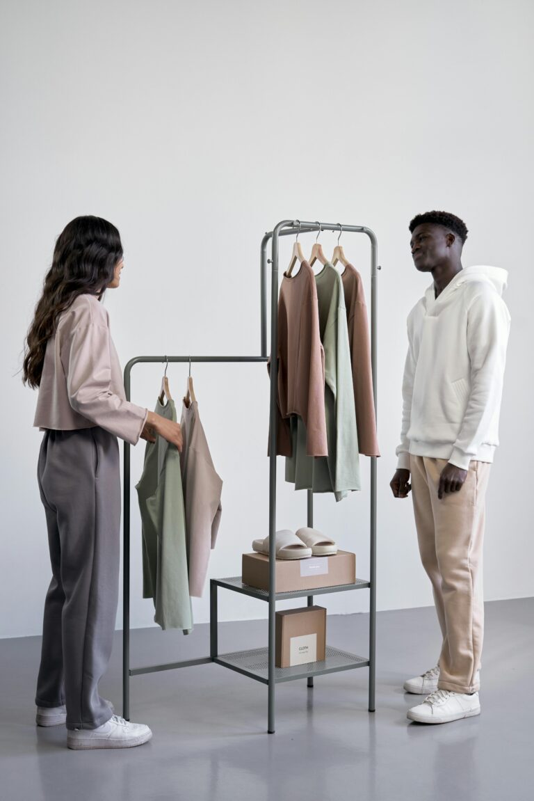 Dois consumidores observando roupas em exposição minimalista, com foco em experiência de compra.