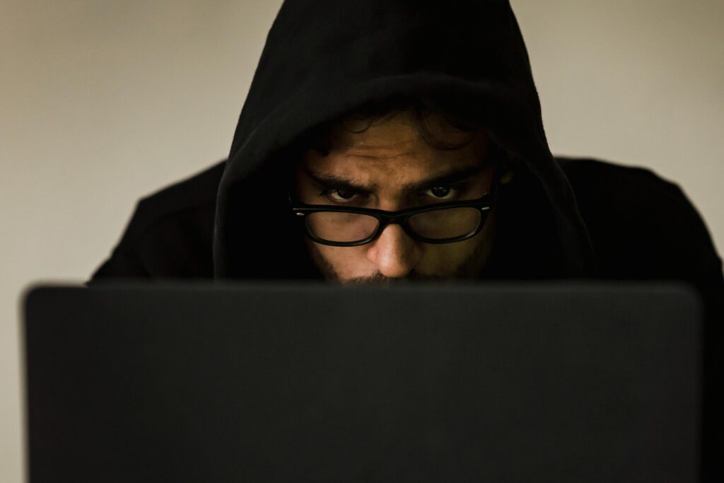 Homem encapuzado usando computador, representando o aumento das fraudes com deepfake no Brasil e os riscos para o setor financeiro e digital.