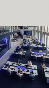 Visão aérea de um escritório corporativo moderno com funcionários trabalhando em computadores.